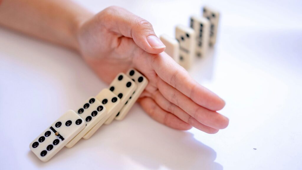 Main stoppant la chute de dominos, illustrant l’arrêt du tabac avec LaserAddict qui met fin à l’effet domino de la dégradation de la santé causée par la cigarette.