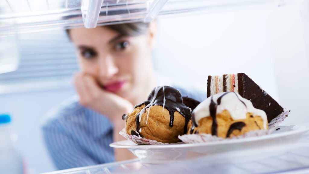 Femme face à des pâtisseries illustrant les envies sucrées émotionnelles, accompagnement LaserAddict pour l’addiction au sucre et l’équilibre émotionnel