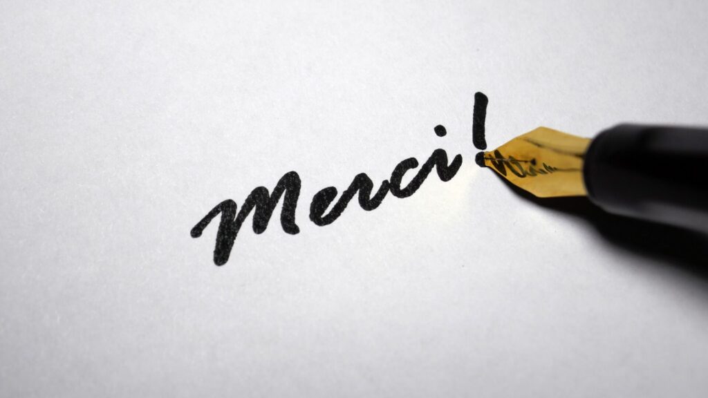 Stylo plume écrivant le mot « merci », symbole de gratitude et d’engagement humain chez LaserAddict