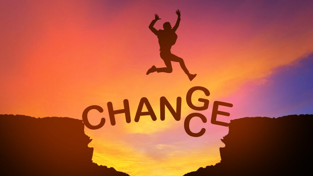 Un homme en plein saut entre deux falaises, avec les mots « chance » derrière lui et « change » sous ses pieds, symbolisant le courage de changer de vie et de saisir une nouvelle opportunité.