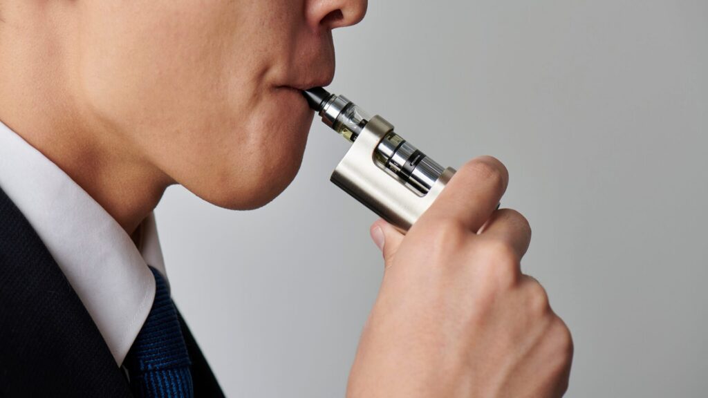 Homme vapotant une cigarette électronique, illustrant les risques de vapoter et l'alternative qu'offre l’accompagnement LaserAddict pour arrêter la nicotine pour amélioration de la santé.